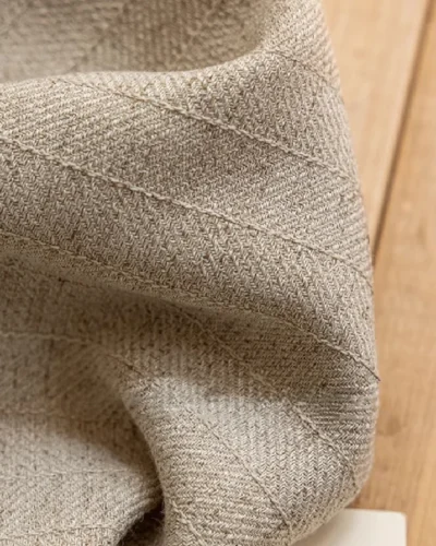 Beige linen fabric close-up showing natural plain weave texture.