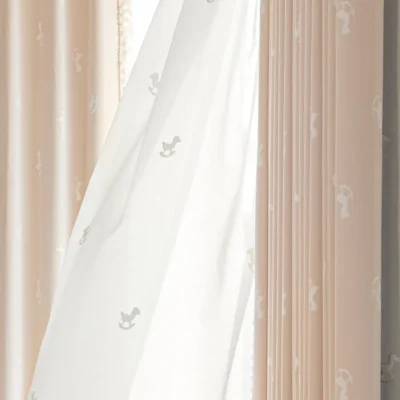 Soft light filtering through sheer curtain layered over rocking horse jacquard kids curtain in pastel pink