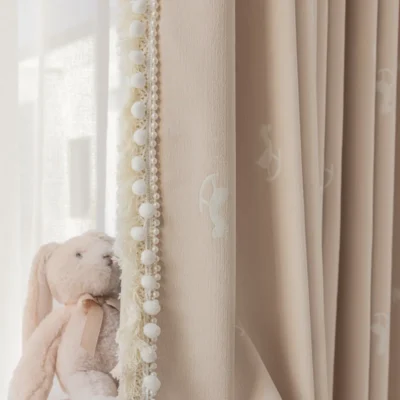 Close-up of pastel jacquard kids curtain with rocking horse pattern and decorative trim beside plush toy