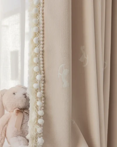 Close-up of pastel jacquard kids curtain with rocking horse pattern and decorative trim beside plush toy