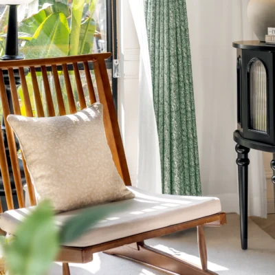 Green textured curtain in natural-lit room with wooden chair, ideal for Japandi interiors