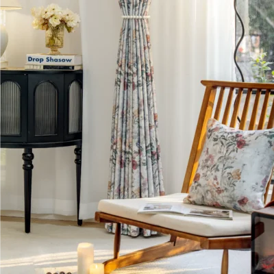 Full-length botanical print curtains with soft floral patterns, styled in a minimalist room with wooden furniture.
