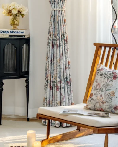 Full-length botanical print curtains with soft floral patterns, styled in a minimalist room with wooden furniture.