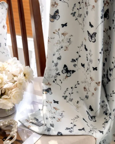 Butterfly print curtain hanging in natural light, with floral patterns and soft botanical details.