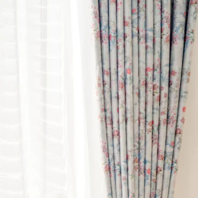 Bird and floral curtain with gentle pleats and light filtering beside window