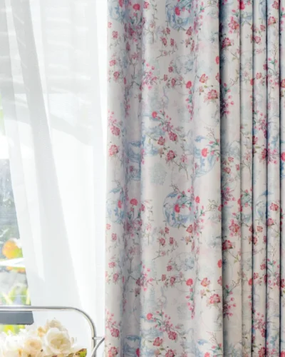 Bird and floral curtain in soft pastel tones, fully drawn beside a sheer panel