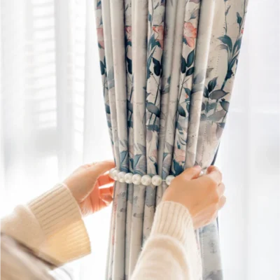 Hands gently pulling Dreamy Meadow floral curtain, showcasing soft fabric texture and elegant draping