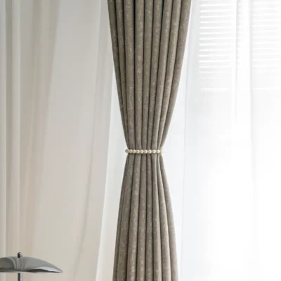 Gilded texture curtain tied at center with soft pleats and natural daylight backdrop.