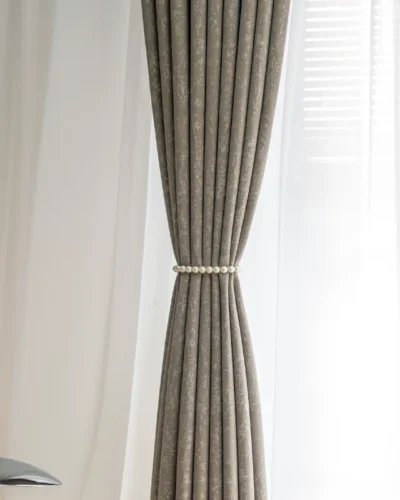 Gilded texture curtain tied at center with soft pleats and natural daylight backdrop.