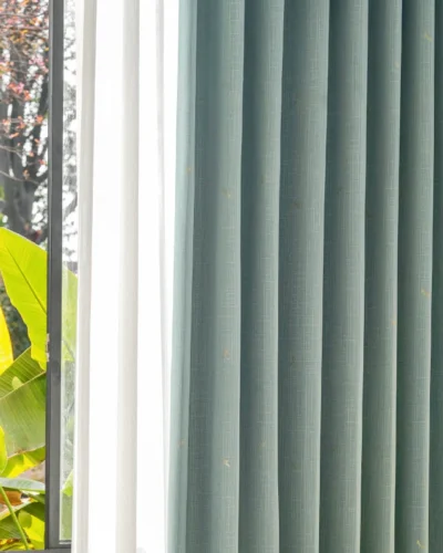 Close-up of blue-grey dragonfly curtain by the window with sunlight filtering through.