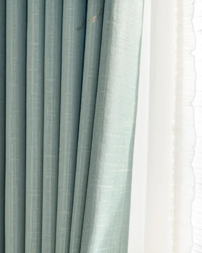 Soft blue dragonfly curtain with pleated folds and sheer panel behind.