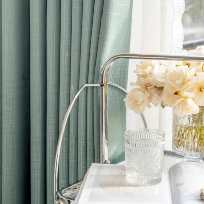 Soft green dragonfly curtain with white sheer panel and floral table decor.