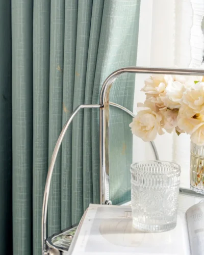 Soft green dragonfly curtain with white sheer panel and floral table decor.