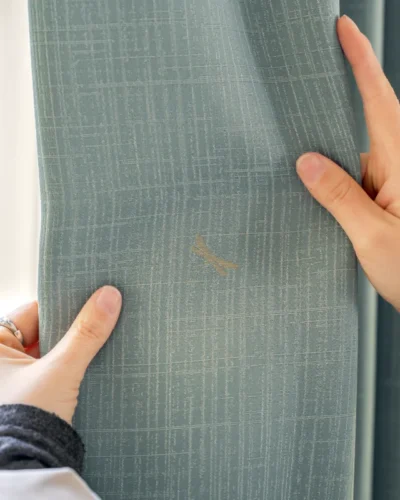 Hand holding green dragonfly weave curtain with subtle embroidery detail.