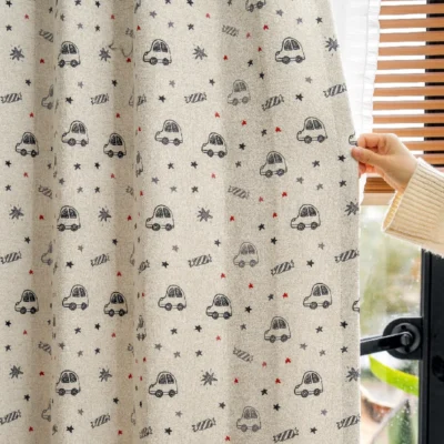 Hand pulling back cartoon car curtain with star pattern in kids room