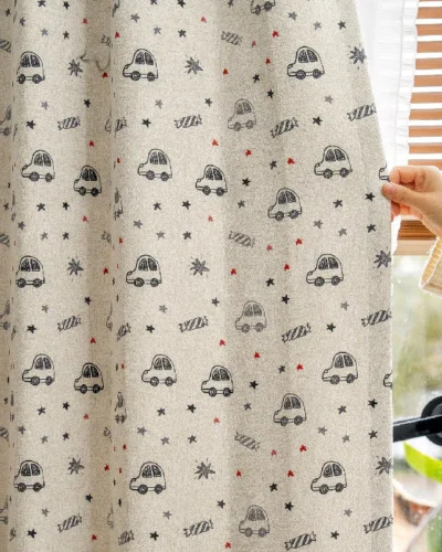Hand pulling back cartoon car curtain with star pattern in kids room