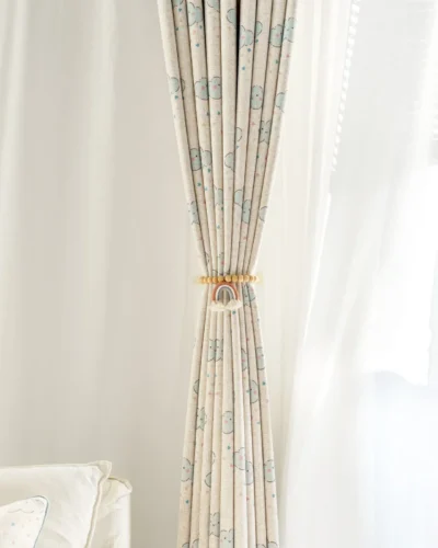 Smiling cloud curtain pulled back with tieback in a bright children’s room