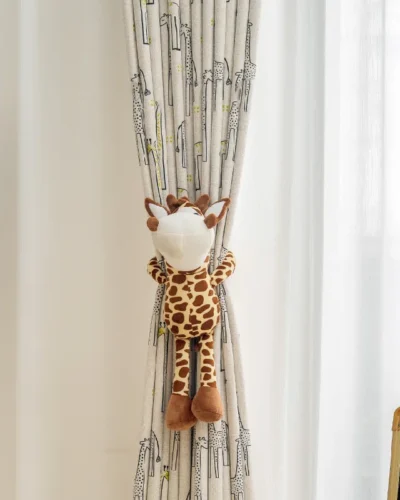 Giraffe print curtain tied with plush toy in softly lit children’s room