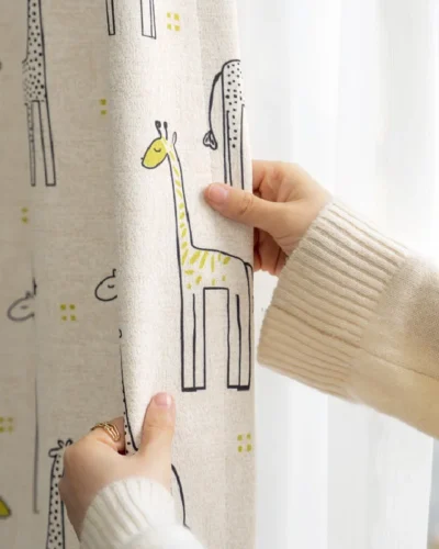 Hand touching giraffe print curtain in children's room with natural light