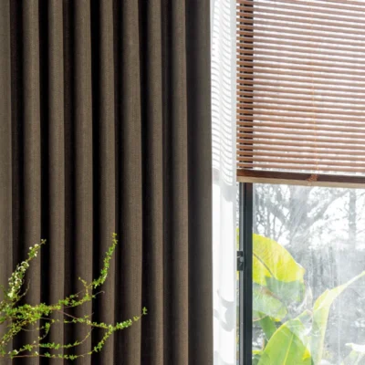 Close-up of Earthline Curtain in charcoal brown – textured fabric softly filtering light near a window.