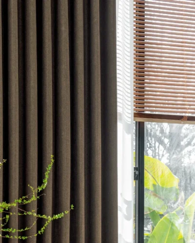 Close-up of Earthline Curtain in charcoal brown – textured fabric softly filtering light near a window.