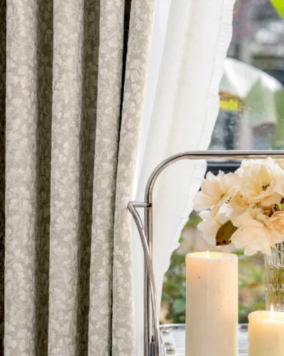 Floral Realm Curtain in soft beige, styled beside flowers and candles in a serene setting