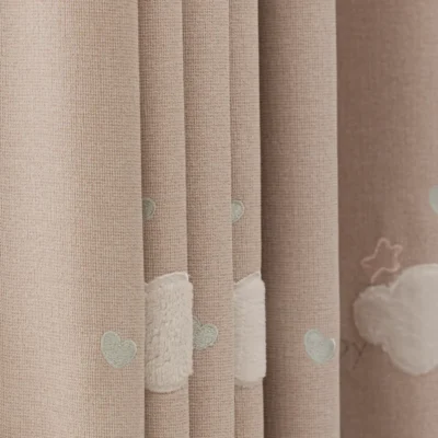 Close-up of cloud embroidery on pink kids curtain with soft textured fabric.