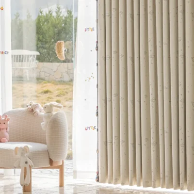 Close-up of embroidered space curtain with yellow planet details, neatly pleated and softly draping in a kids' room