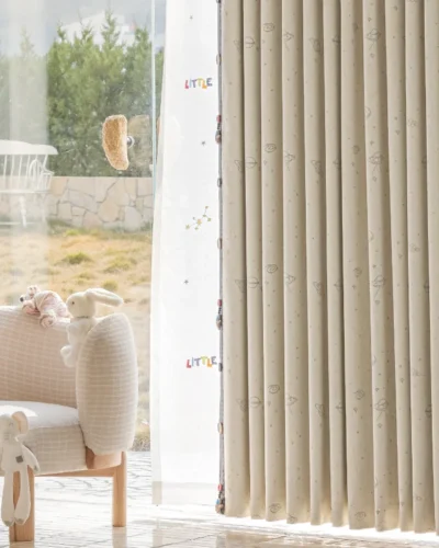 Close-up of embroidered space curtain with yellow planet details, neatly pleated and softly draping in a kids' room