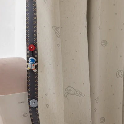 Close-up of fine embroidery on kids' space-themed curtain with stitched planet and star details