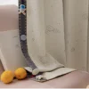 Bottom hem of embroidered kids curtain with planet and star design, shown with toys and sheer fabric lining
