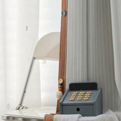 Close-up of Whisper Stripe Curtain in mist grey with white sheer layer and vintage-style phone décor