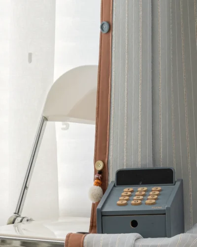 Close-up of Whisper Stripe Curtain in mist grey with white sheer layer and vintage-style phone décor
