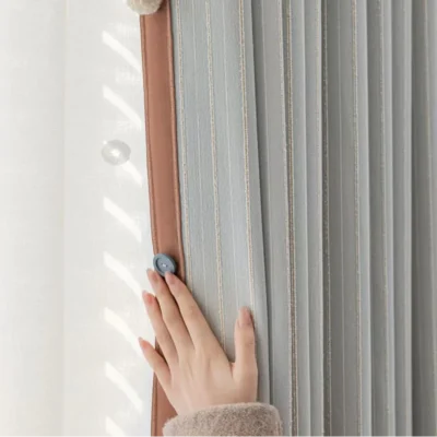 Hand touching Whisper Stripe Curtain in mist grey, highlighting soft texture and gentle drape by the window
