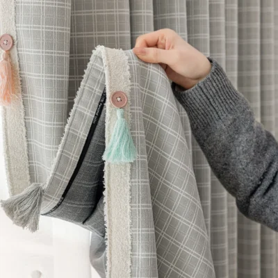 Close-up of Whisper Glow Curtain with soft British plaid jacquard texture and hand-holding detail