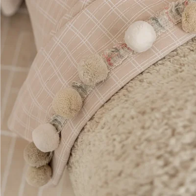 Close-up of Gridline Whisper Curtain fabric showing woven grid texture and pompom trim detail