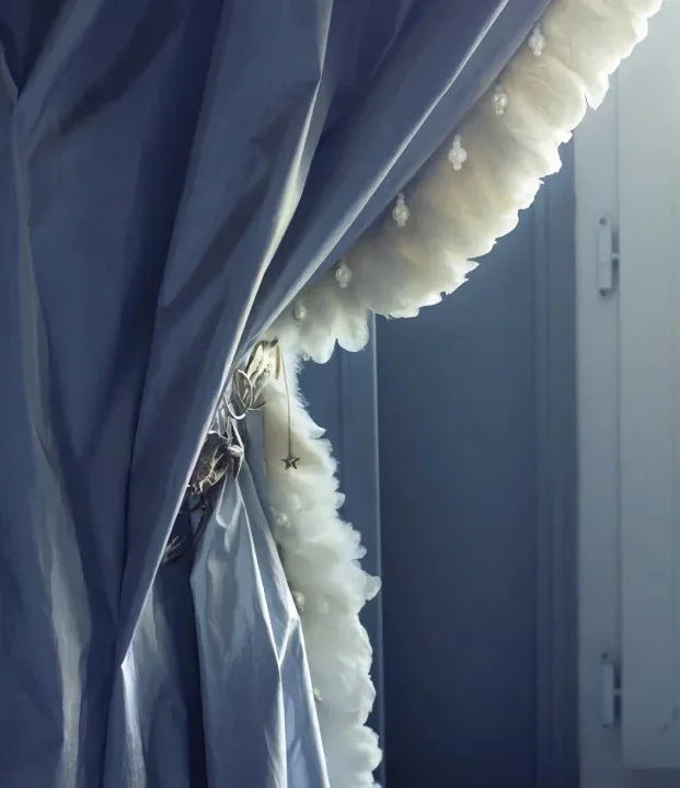 White feather curtain trim detail on blue drape by window