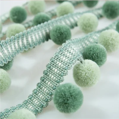 Soft sage green velvet pom pom fringe trim with textured ribbon for curtain or cushion edging.