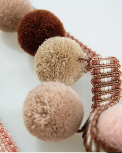 Warm-toned pom pom fringe trim in blush, caramel, and dusty pink — ideal for cozy or vintage interiors