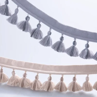 Side-by-side view of single-layer tassel fringe trims in gray blue and beige tones, showing color options