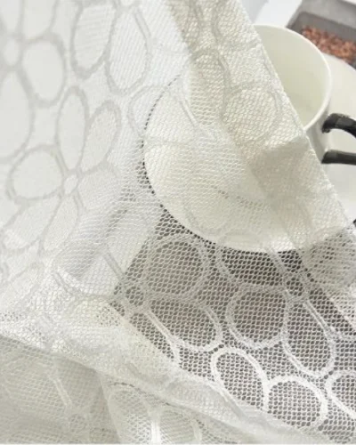 Close-up of Lightflow lace curtain fabric showing circular woven pattern and texture