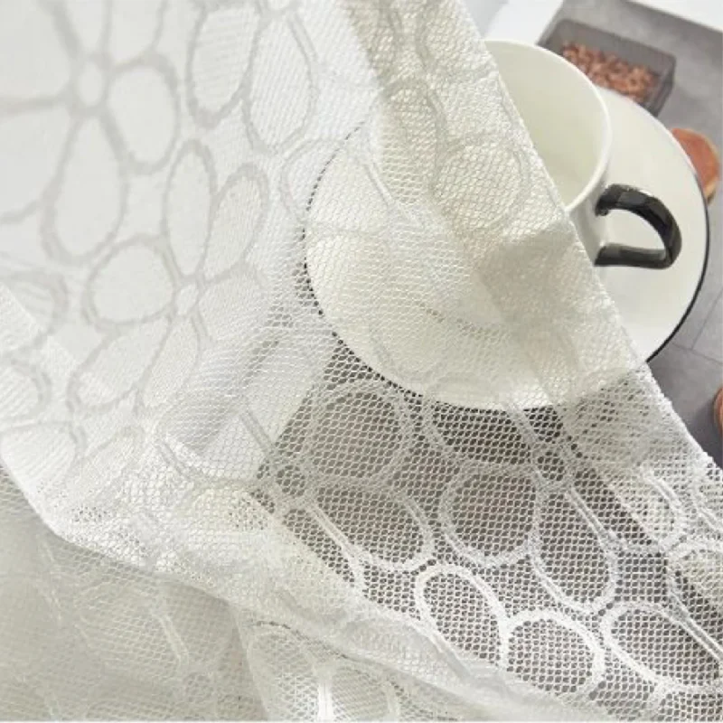Close-up of Lightflow lace curtain fabric showing circular woven pattern and texture