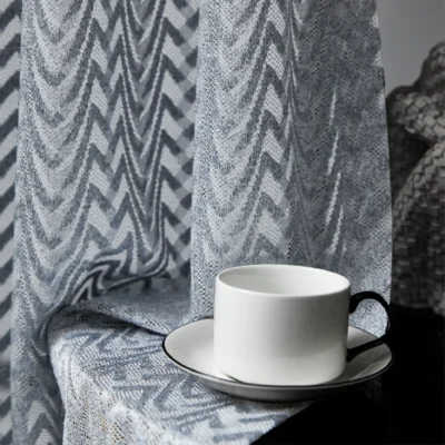 Close-up of zigzag sheer curtain with coffee cup on side table