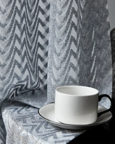 Close-up of zigzag sheer curtain with coffee cup on side table