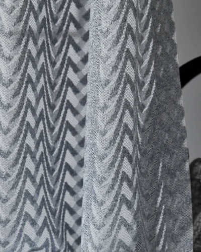 Zigzag sheer curtains hanging in a modern room, textured light voile in soft gray tones