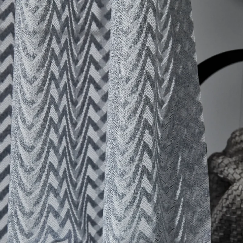 Zigzag sheer curtains hanging in a modern room, textured light voile in soft gray tones