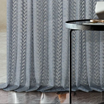Zigzag sheer curtain draping to the floor beside a round table