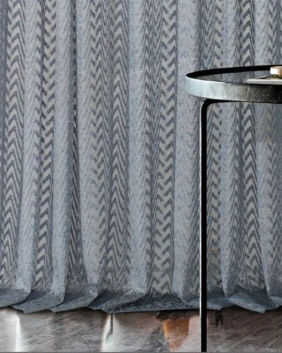 Zigzag sheer curtain draping to the floor beside a round table