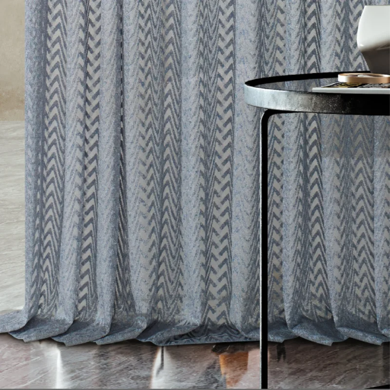 Zigzag sheer curtain draping to the floor beside a round table