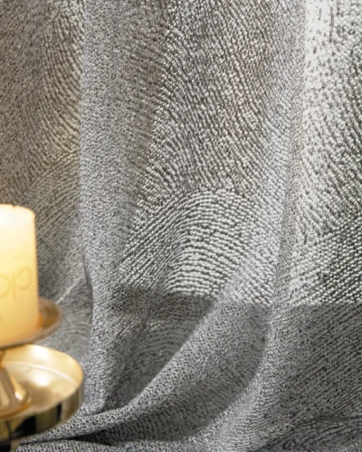Ripple textured sheer curtain illuminated by warm candlelight, showing soft wave patterns.